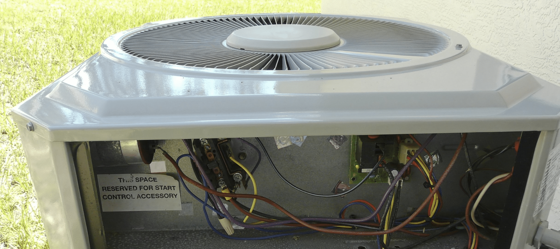 closeup outdoor hvac unit with side panel removed showing the wiring and other components inside