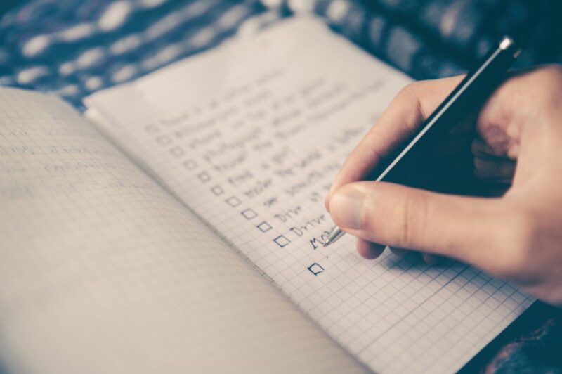 closeup of person writing in journal making a checklist