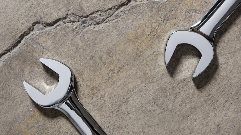 closeup of two wrenches laying on a concrete floor
