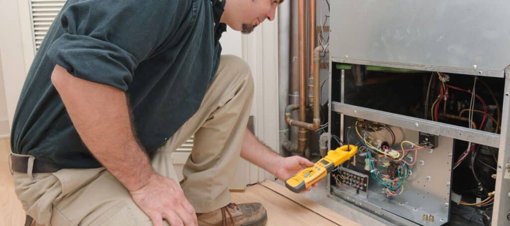 hvac technician using a manifold pressure checker to perform repairs on furnace