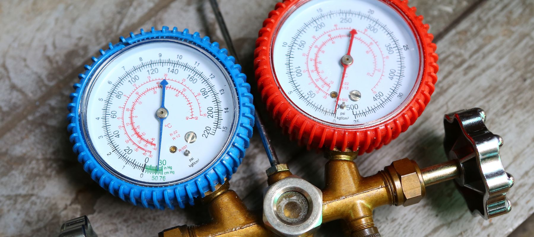 A close-up of red and blue HVAC gauges used to measure pressure and temperature for air conditioning systems