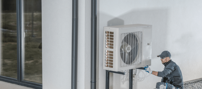 hvac technician working on a heat pump unit at a residential home