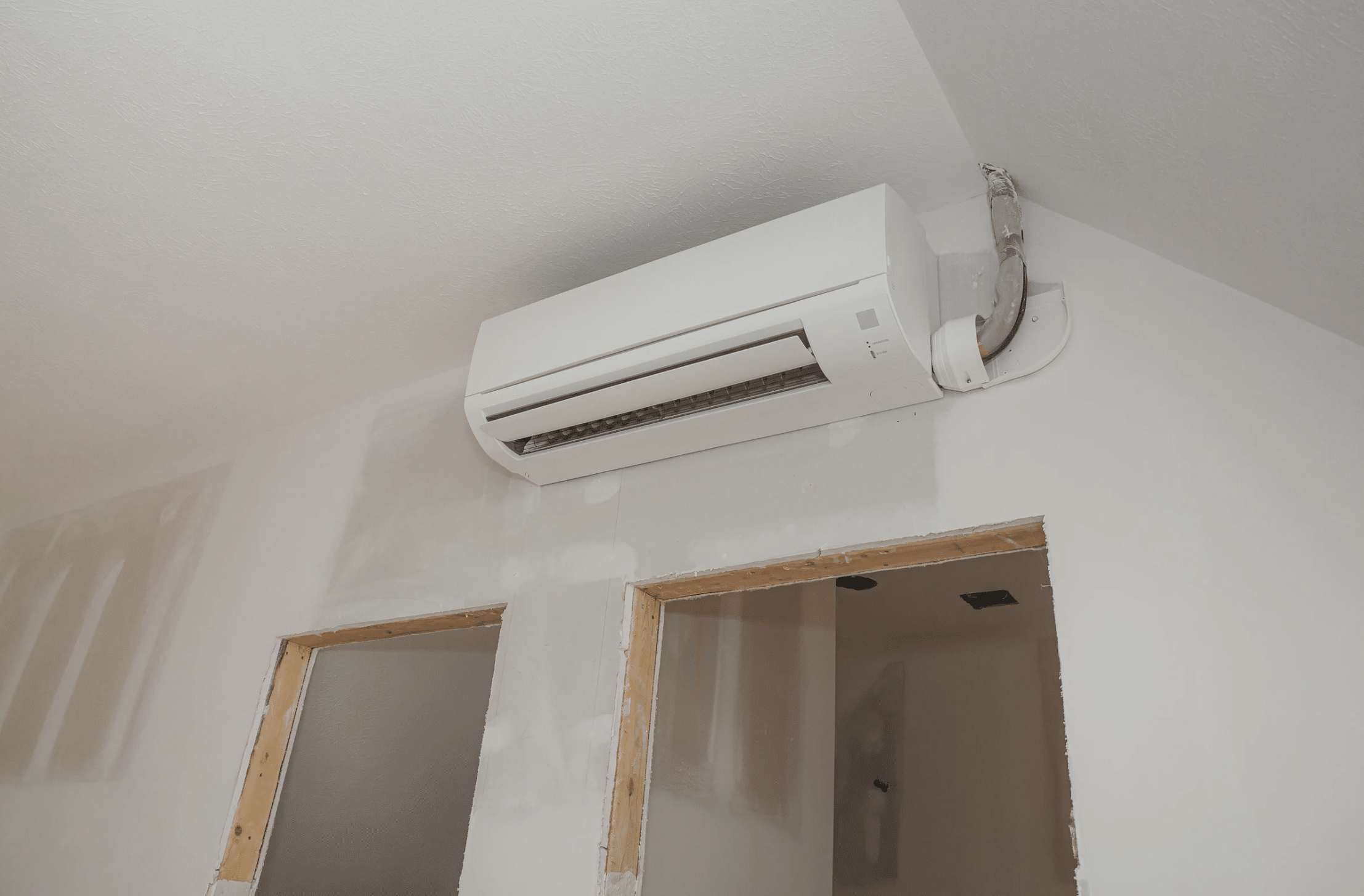ductless ac unit positioned on a wall above two doors