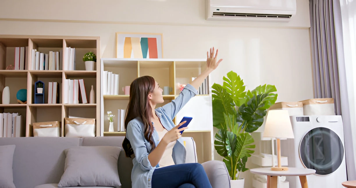 Woman feeling the air coming out of an air conditioning unit or heat pump