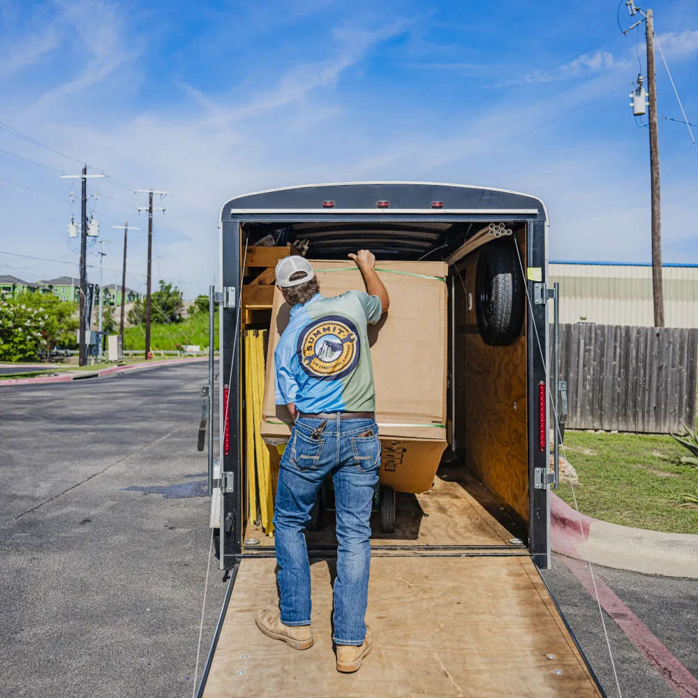 Summit AC crew member loading HVAC equipment into vehicle