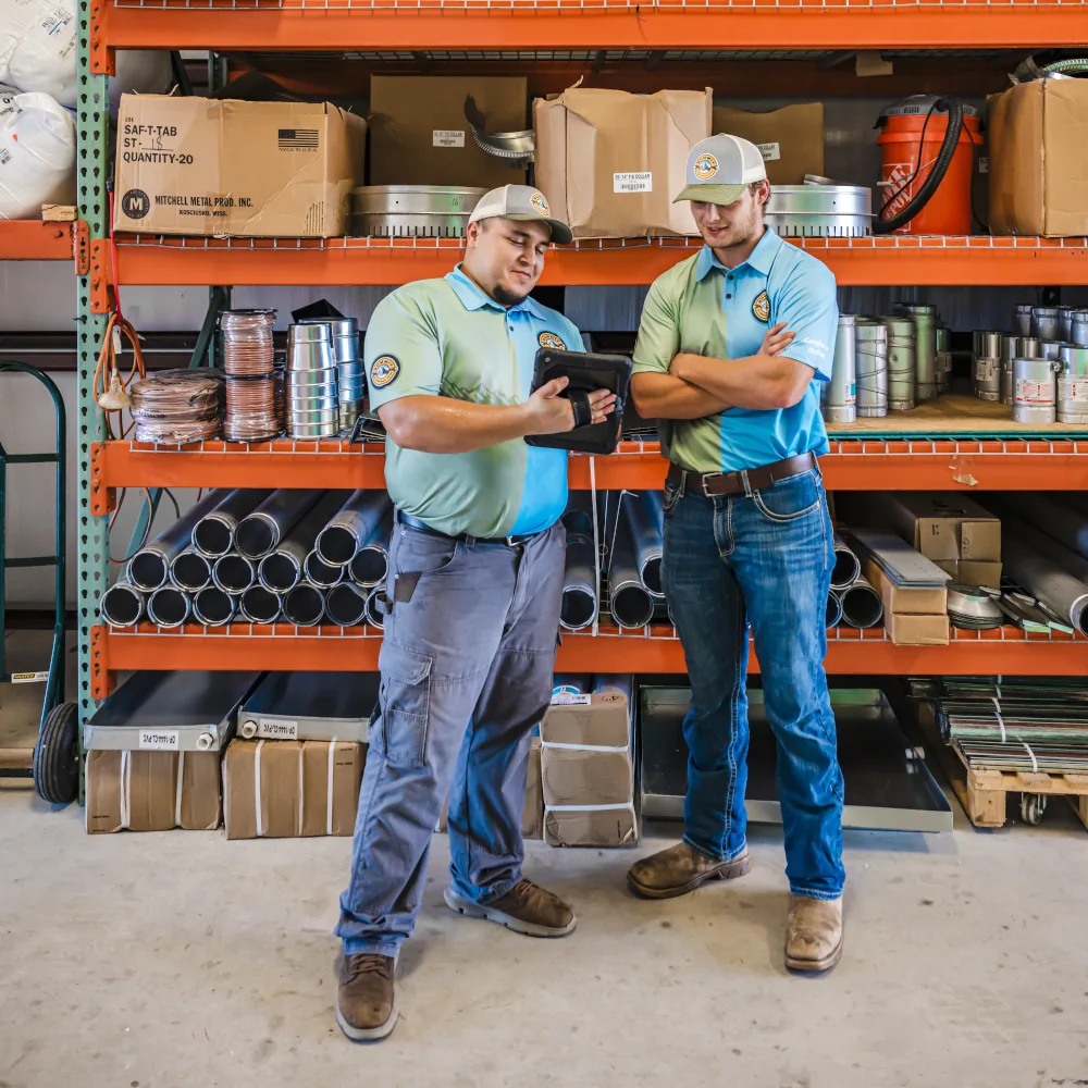 2 Summit AC team members talking and looking at a tablet inside a storage room