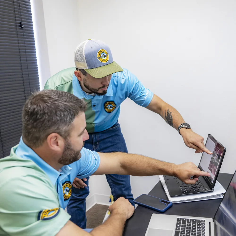 2 members of the Summit Air Conditioning & Heating team looking at a laptop screen