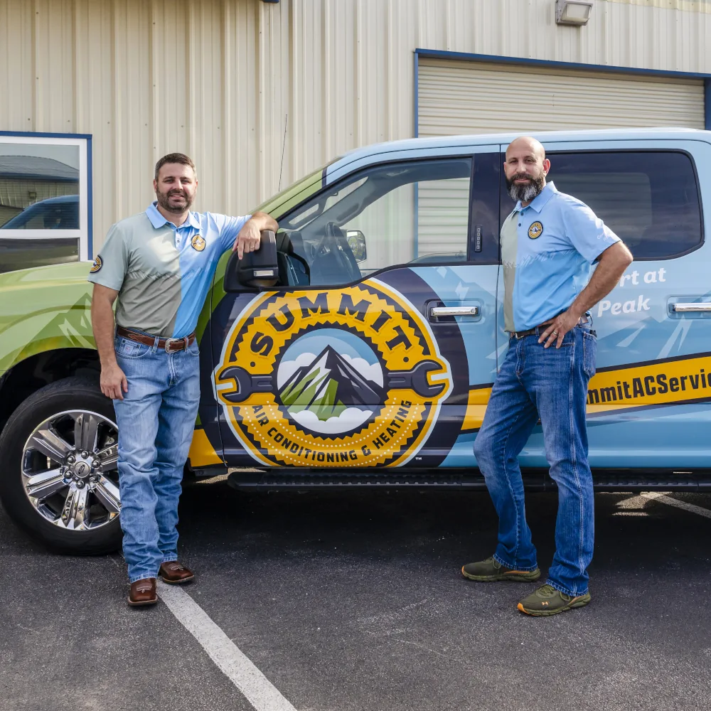 Two Summit AC team members posing outside a company truck