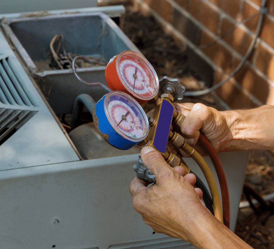closeup of a technician reading pressure with a tool on an outdoor air conditioning unit